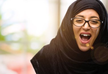 Büyük başarı, güç, enerji ve olumlu duygular ifade hijab mutlu ve heyecanlı kutluyor zafer giyen genç Arap kadın. Yeni iş neşeli kutluyor