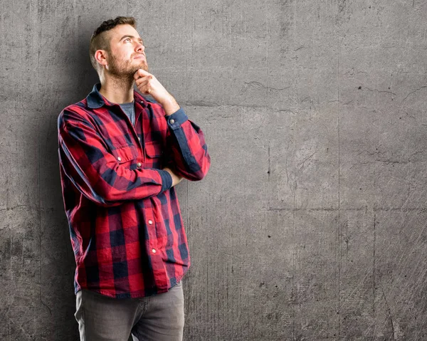 Young handsome man thinking and looking up expressing doubt and wonder