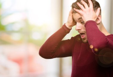 Yakışıklı genç adam stresli kafasına, panik içinde dehşete ellerini tutmak, bağırarak