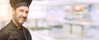 Kıdemli şef şapkalı kendinden emin ve mutlu bir büyük doğal gülümseme davet ile restoran mutfağa girmek adam, yemek