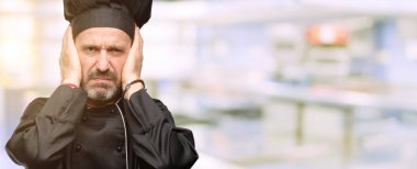 Üst düzey aşçı adam, aşçı şapkası kulakları rahatsız edici gürültü, görmezden kapsayan kulak işitme ses önlemek için fişler. Gürültülü müzik bir sorundur. lokanta mutfağı