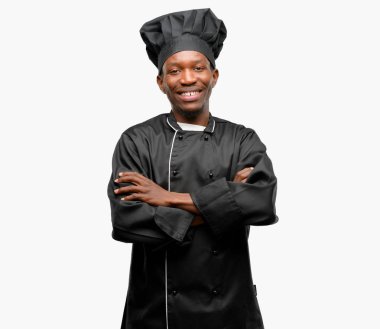 Genç siyah giyen chef şapka çapraz kolları kendinden emin ve mutlu bir büyük doğal gülümseme gülmek ile olan yemek