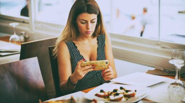 Bir fotoğraf için ona yiyecek çekici smartphone kullanan genç kadın