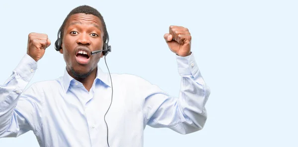 Black man consultant of call center happy and excited celebrating victory expressing big success, power, energy and positive emotions. Celebrates new job joyful