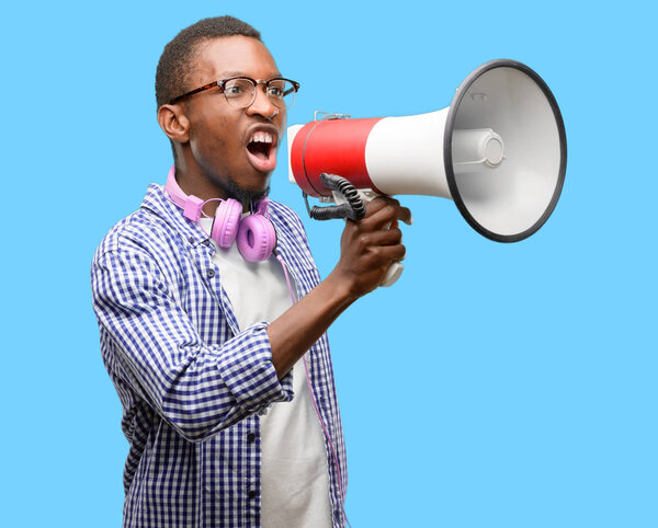 Африканский чернокожий студент со смартфоном общается громко, держа мегафон, выражая успех и позитивную концепцию, идею для маркетинга или продаж

