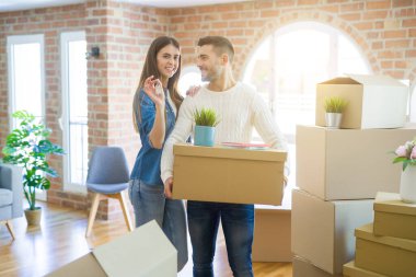 Genç çift yeni bir eve hareket, yeni dairenin anahtarlarını gösteren aşk sarılmak çok mutlu gülümseyen