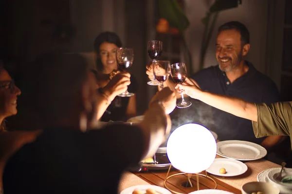 Beautiful family toasting with cup of wine on dinner smiling at terrace