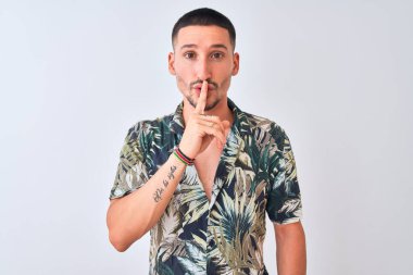 İzole edilmiş arka planda Hawaii tişörtü giyen yakışıklı genç adam sessiz olmak istiyor. Sessizlik ve gizli konsept.