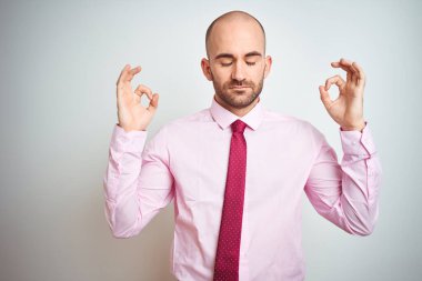 Soyutlanmış arka planda pembe kravat takan genç iş adamı rahatla ve parmaklarıyla meditasyon hareketi yaparken gözlerin kapalı gülümse. Yoga konsepti.