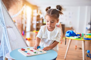 Anaokulunda matematik oyunu oynayan genç ve güzel bir çocuk.