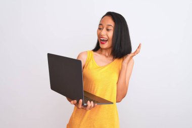 Genç, güzel Çinli bir kadın dizüstü bilgisayar kullanıyor. İzole edilmiş beyaz arka plan üzerinde duruyor. Çok mutlu ve heyecanlı.