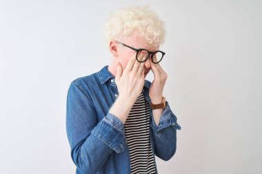 Kotlu gömlek ve gözlük takan genç sarışın adam izole edilmiş beyaz arka planda yorgunluk ve baş ağrısı için gözlerini ovuşturuyor, uykulu ve yorgun ifade ediyor. Görüş sorunu