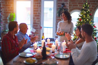 Mutlu ve kendinden emin gülümseyen güzel bir aile. Kavrulmuş hindiyi göstermek ve evde Noel 'i kutlamak.