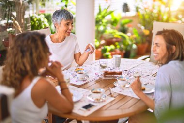 Genç ve güzel bir kız mutlu ve kendinden emin bir şekilde terasta oturmuş bir fincan kahve içiyor.