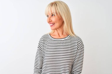 Orta yaşlı kadın, donanma çizgili tişört giyiyor izole edilmiş beyaz arka planda duruyor yüzünde gülümseme, doğal bir ifade ile yan yana bakıyor. Kendinden emin gülen.