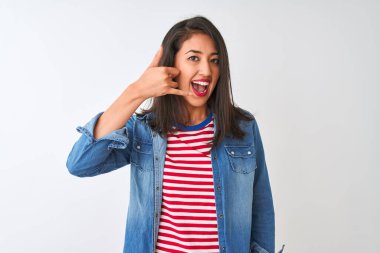İzole edilmiş beyaz arka plan üzerinde çizgili t-shirt ve kot gömlek giyen genç Çinli kadın telefonla el ve parmaklarıyla telefonla konuşuyor gibi gülümsüyor. İletişim kavramları.
