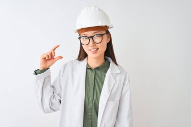 Genç Çinli mühendis kadın, izole edilmiş beyaz arka planda gözlük takıyor gülümsüyor ve el hareketleriyle küçük beden işareti yapıyor, parmakları bakıyor ve kameraya bakıyor. Ölçü kavramı.