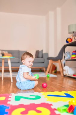 Anaokulunda küçük renkli toplarla oynayan güzel bir çocuk.