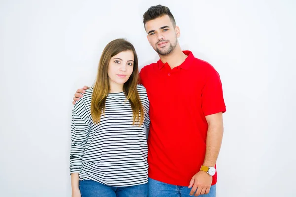 Young beautiful couple hugging together over white isolated background with a confident expression on smart face thinking serious