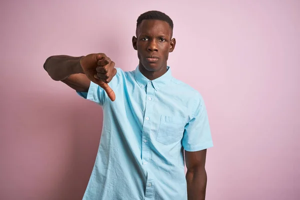 青いカジュアルなシャツを着たアフリカ系アメリカ人男性がピンクの背景の上に立っている 悪い表現 — ストック写真