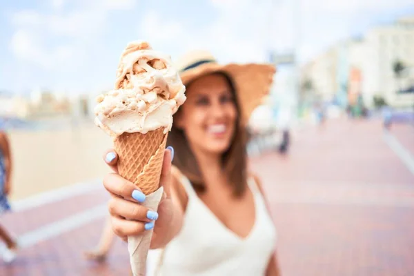 Young beautiful woman eating ice cream cone by the beach on a sunny day of summer on holidays
