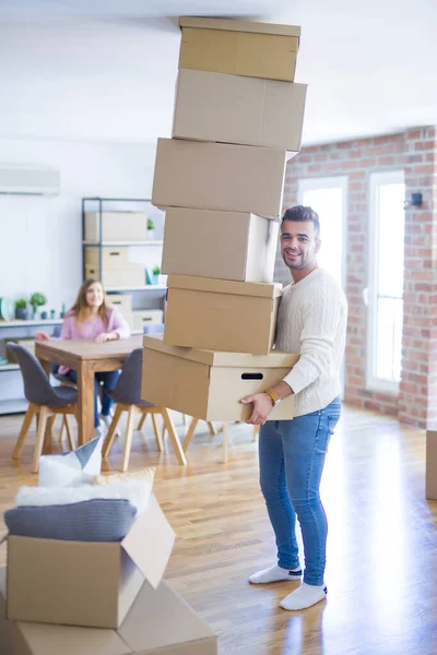 Young couple moving to a new house, man holding cardboard boxes