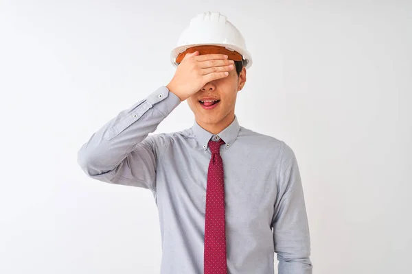 中国の建築家の男がネクタイとヘルメットを着用し 孤立した白い背景の上に立って笑顔と驚きのために目をカバー顔に手で笑う ブラインドコンセプト — ストック写真