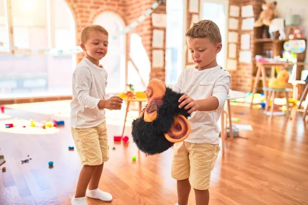 Adorable blonde twins playing wearing monkey mask around lots of toys at kindergarten