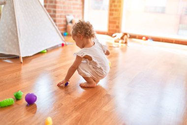 Renkli oyun odasında beyaz güzel bir bebek oyuncaklarla oynuyor. Anaokulunda mutlu ve şen şakrak.
