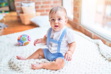 Anaokulunda battaniyenin üzerinde oturan güzel çocuk.