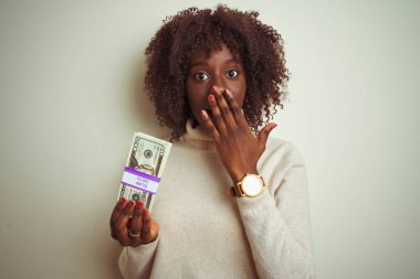 Genç Afrikalı Afrikalı bir kadın, izole edilmiş beyaz arka planda duran dolarları tutuyor. Ağzı kapalı, utancından ağzı açık, korkusunun dışa vurumu, sessizlikten korkması, gizli konsept.