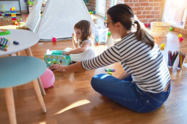 Güzel öğretmen kadın ve bebek anaokulunda bir sürü oyuncakla oynuyorlar.