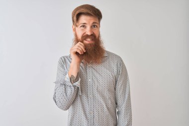 İzole edilmiş beyaz arka plan üzerinde dikilmiş, elleri çenesinde soru soran, düşünceli bir İrlandalı genç adam. Düşünceli bir yüzle gülümsüyor. Şüphe kavramı.