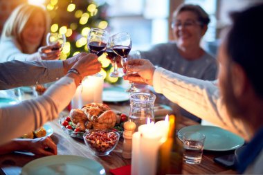 Aile ve arkadaşlar Noel arifesini geleneksel yemek ve dekorasyonla birlikte evde yemek yiyorlar. Hep birlikte masaya oturuyorlar.