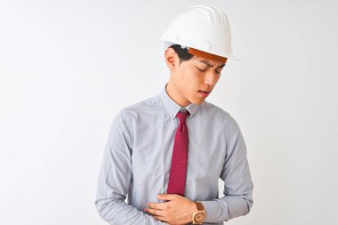 Miğfer ve kravat takan Çinli mimar midesi bulanan, acı veren bir hastalıktan dolayı izole edilmiş beyaz arka planda duruyor. Ache kavramı.