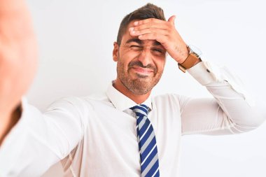 Genç yakışıklı iş adamı, izole edilmiş arka planda akıllı telefon kullanarak özçekim yapıyor. Elleri ve ayakları yere basıyor, utanç ve şaşkınlık içinde, sinirli ve hayal kırıklığına uğramış bir halde. Hata için korku ve üzüntü.