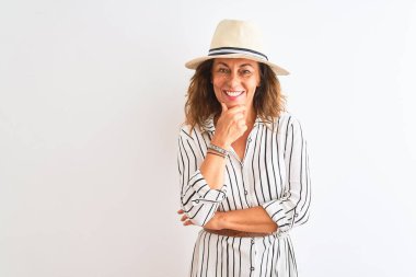 Orta yaşlı iş kadını, çizgili elbise ve şapkalı, izole edilmiş beyaz arka planda kameraya gülümseyen, kolları çapraz ve çenesi havada bir şekilde bakıyor. Olumlu düşünüyorum..