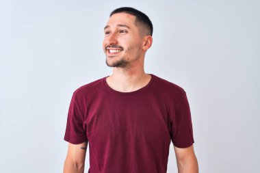 Soyutlanmış arka planda duran yakışıklı genç adam yüzünde gülümseme, doğal bir ifade ile yan yana bakıyor. Kendinden emin gülen.