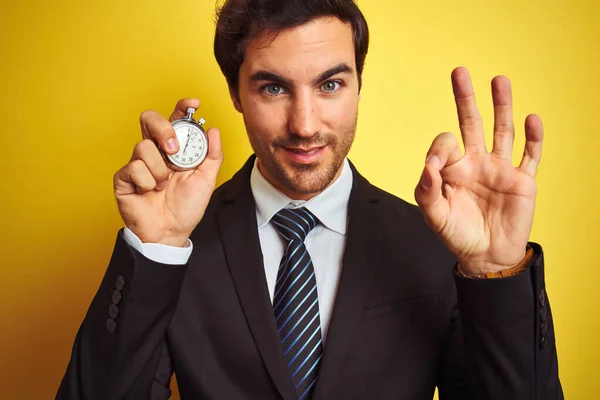 Νεαρός Όμορφος Επιχειρηματίας Κρατώντας Χρονόμετρο Στέκεται Πάνω Από Απομονωμένο Κίτρινο — Φωτογραφία Αρχείου