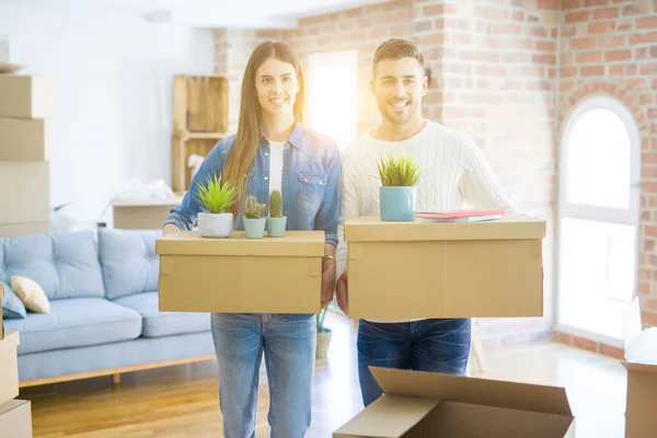Junges Paar zieht in ein neues Zuhause und lächelt glücklich mit Karton — Stockfoto