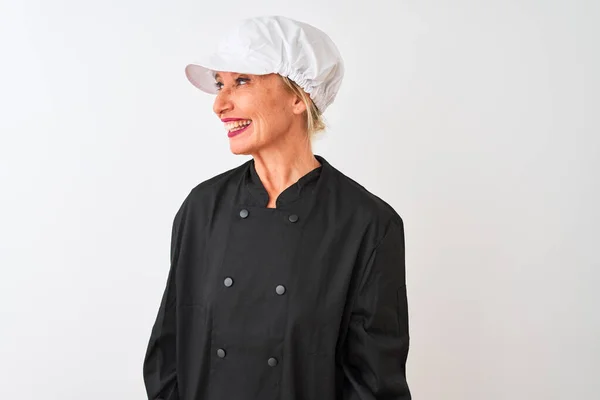 Middle age chef woman wearing uniform and cap standing over isolated white background looking away to side with smile on face, natural expression. Laughing confident.