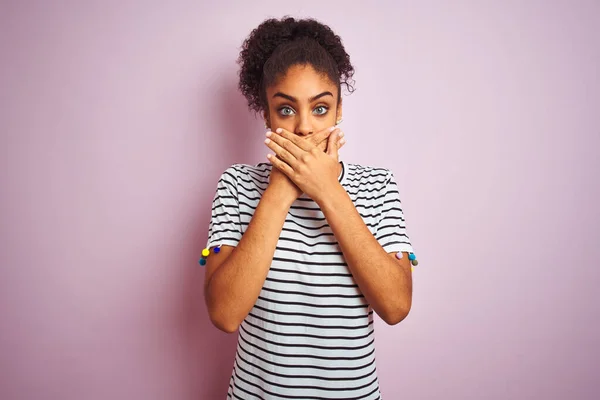 African american woman wearing navy striped t-shirt standing over isolated pink background shocked covering mouth with hands for mistake. Secret concept.