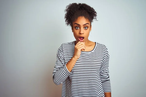 African american woman wearing navy striped t-shirt standing over isolated white background Looking fascinated with disbelief, surprise and amazed expression with hands on chin