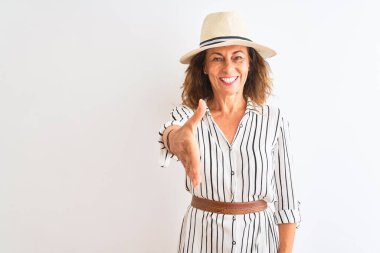 Orta yaşlı bir iş kadını, çizgili elbise ve şapka giyip izole edilmiş beyaz arka plan üzerinde dostça gülümseyerek selamlama ve hoş geldin diyor. Başarılı bir iş..