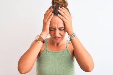 Kızıl saçlı genç bir kadın, izole edilmiş arka planda, acı ve migrenden dolayı çaresiz ve stresli bir baş ağrısı çeken bir çörek giyiyor. Ellerini başının üstüne koy..