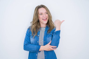 Güzel sarışın kız, mavi gözlü, beyaz tenli, mutlu yüzüyle gülümseyen ve baş parmağıyla yan tarafı gösteren..