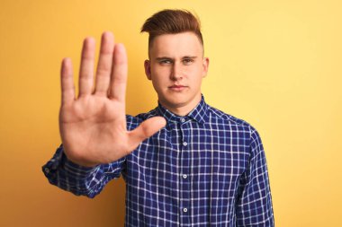 Sarı arka planda duran rahat tişörtlü genç ve yakışıklı bir adam avucunun içinde şarkı söylemeyi kesiyor. Yüzünde olumsuz ve ciddi bir jest olan uyarı ifadesi.