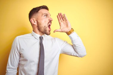 Sarı arka planda zarif beyaz gömlek giyen yakışıklı iş adamı el ele tutuşarak bağırıyor ve çığlık atıyordu. İletişim konsepti.