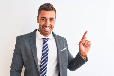 Takım elbiseli ve kravatlı genç yakışıklı bir iş adamı. Yüzünde kocaman bir gülümseme var. Elinle kameraya bakıyor..