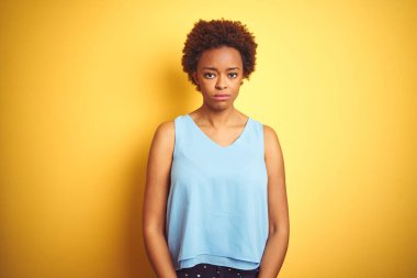 Güzel Afro-Amerikan kadını şık bir gömlek giyerek izole edilmiş sarı arka planda depresif ve üzüntülü, sinirli ve korkmuş bir şekilde ağlıyor. Üzücü ifade.